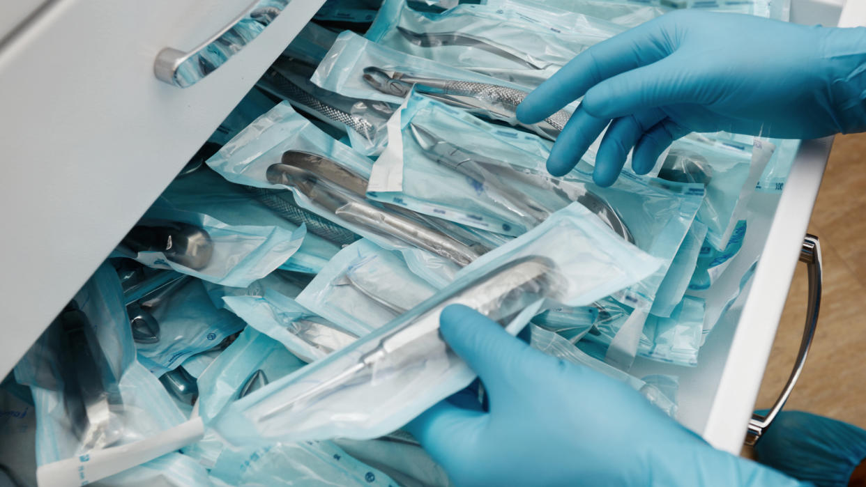 Medical laboratory technician holding a set of sterile disposable instruments - Image.