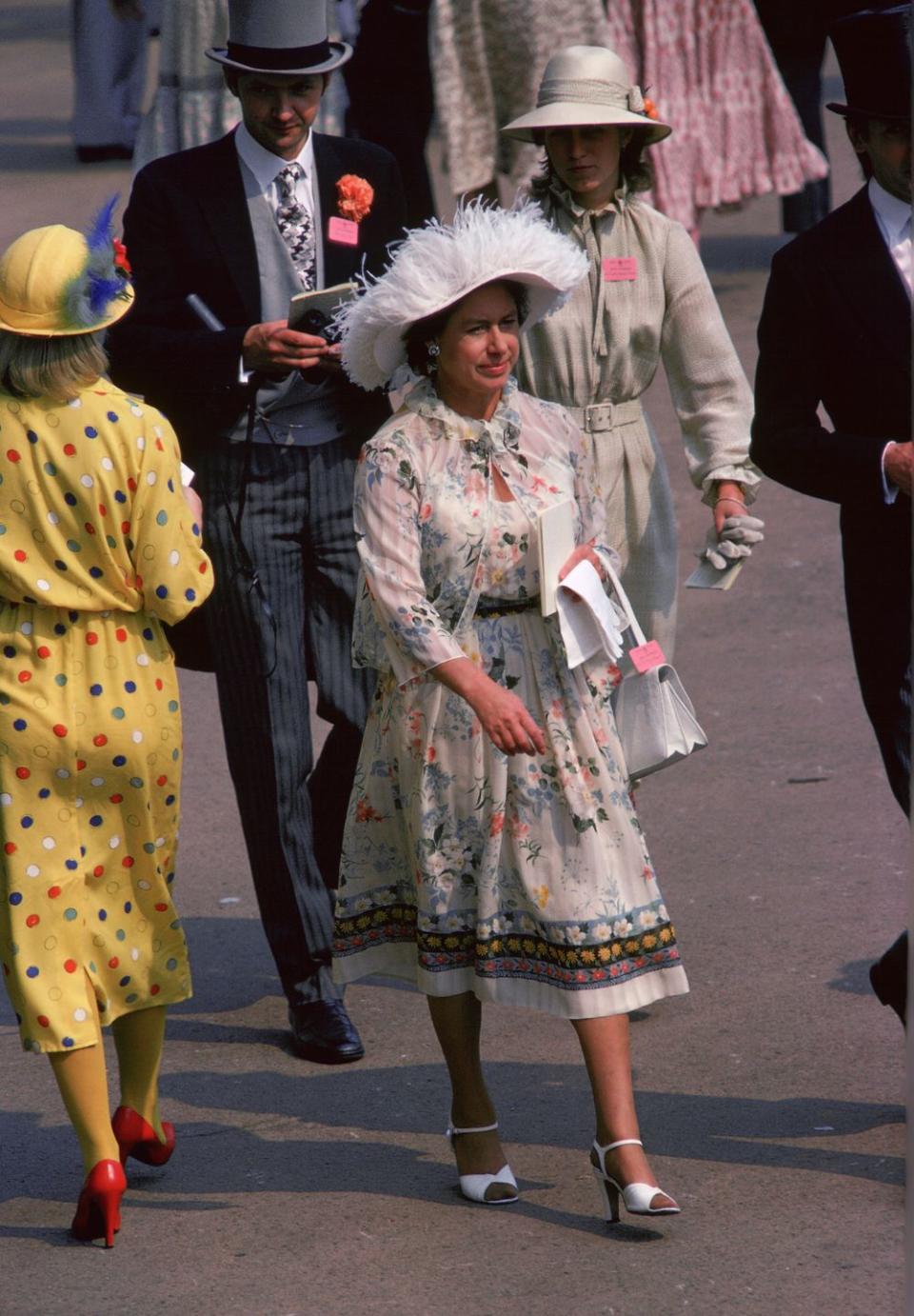 <p>Princess Margaret attends the 1979 Royal Ascot Races in a patterned dress and feathered white hat.</p>