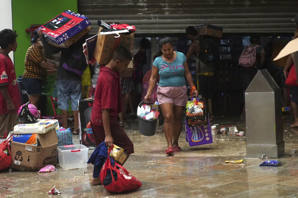 People carry away items they took from a grocery store after Hurricane Otis ripped through Acapulco, Mexico, Wednesday, Oct. 25, 2023. Hurricane Otis ripped through Mexico's southern Pacific coast as a powerful Category 5 storm, unleashing massive flooding, ravaging roads and leaving large swaths of the southwestern state of Guerrero without power or cellphone service. (AP Photo/Marco Ugarte)