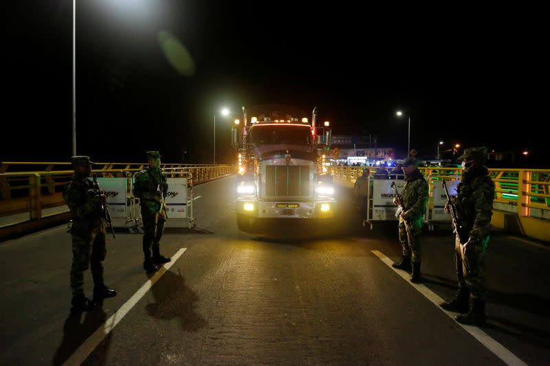 Soldiers keep watch near a trailer truck carrying food at Rumichaca International Bridge between Colombia and Ecuador, after Ecuador's government closed its borders to all foreign travelers due to the spread of the coronavirus disease, in Tulcan