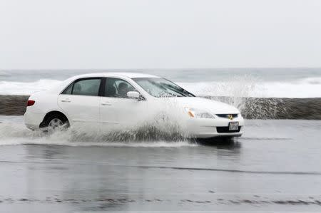 A car makes its way through standing water as a winter storm brings rain and high winds to Cardiff, California December 12, 2014. REUTERS/Mike Blake