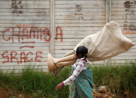 A hawker carries mannequins past graffiti in Mbare township, Harare, Zimbabwe, January 23, 2019. REUTERS/Philimon Bulawayo