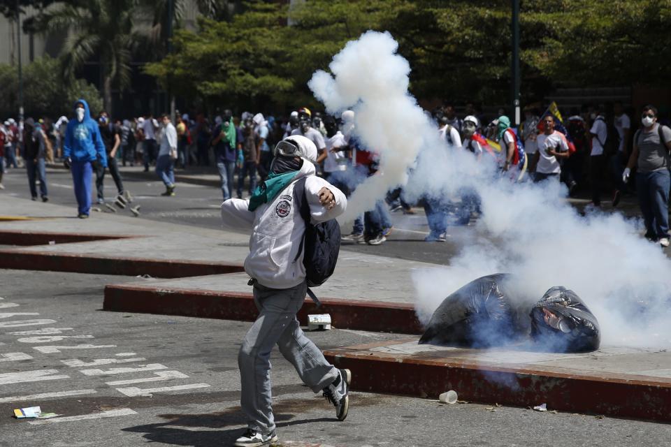 An anti-government protester throws a teargas canister back at the police in Caracas