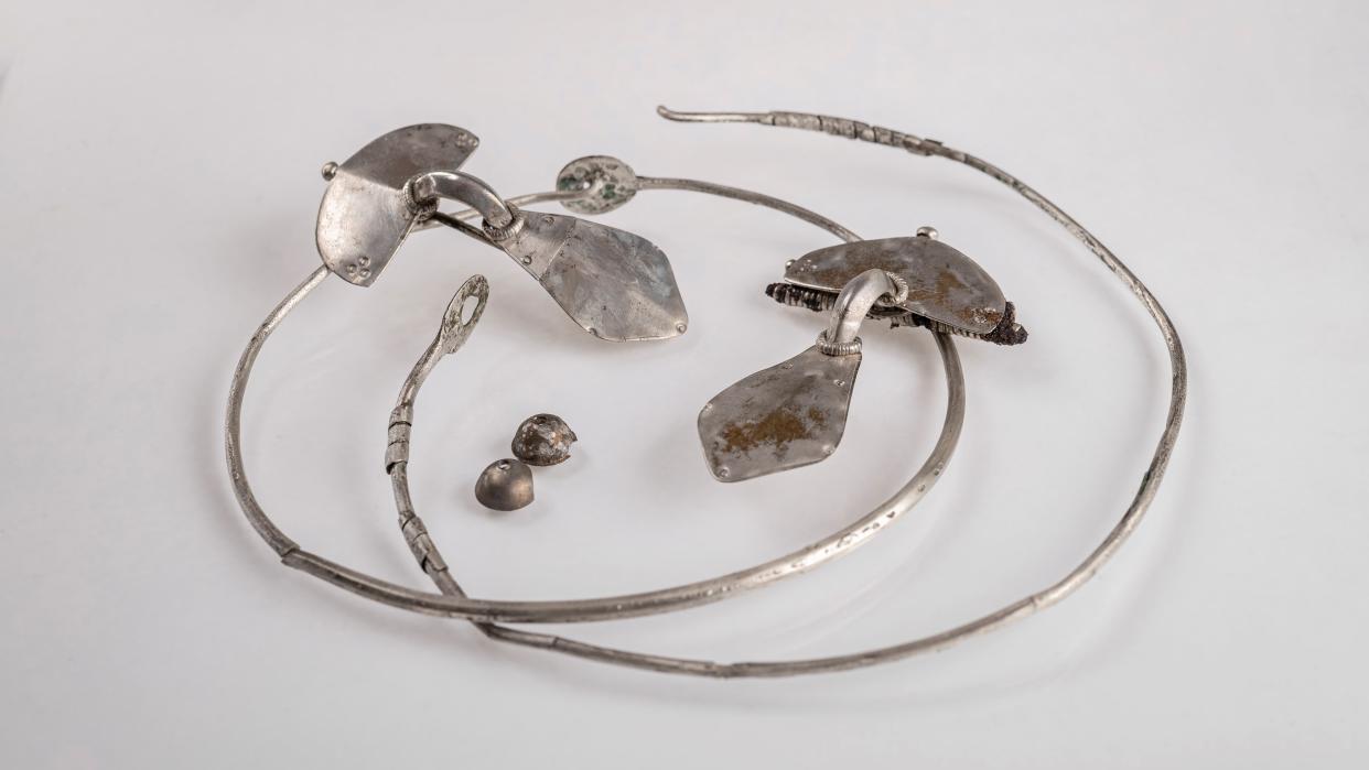  Silver necklaces and brooches against a gray background 