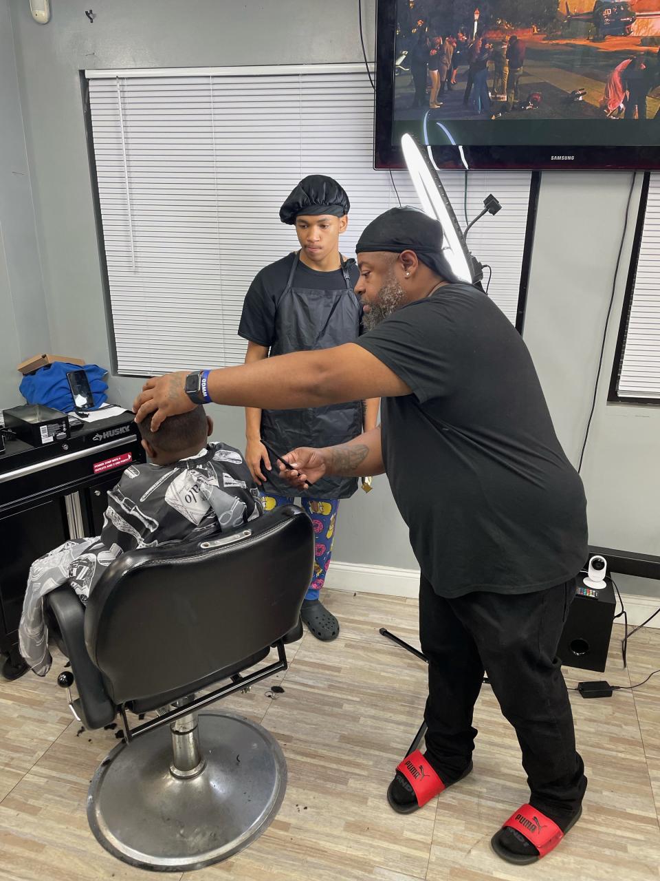 LaVonn Wilson, right, runs a job training program that doubles as a violence prevention initiative at his barbershop, Line 'em Up Barbering, on North Goodman Street. Eleven students in two cohorts have completed the program since last fall.