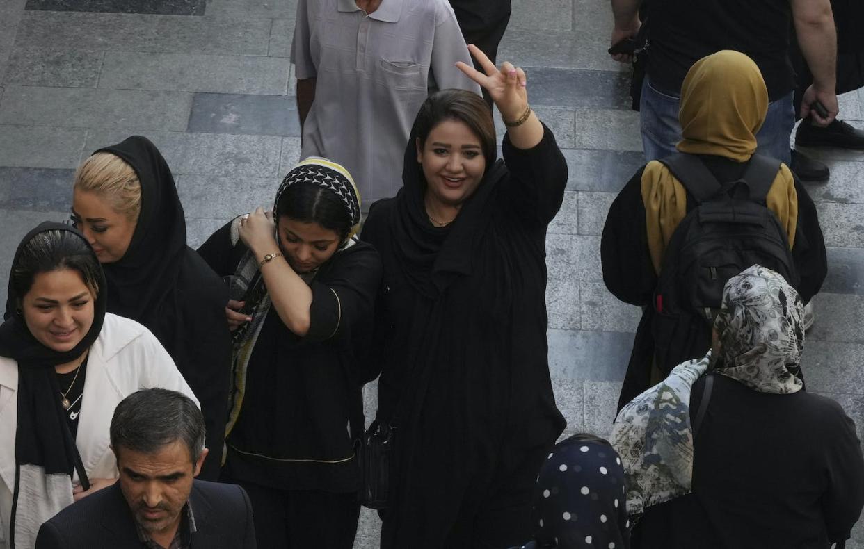 A woman who's not wearing a hijab flashes a victory sign as she walks around in the old main bazaar of Tehran, Iran, on Oct. 1, 2022. Thousands of Iranians have taken to the streets over the last two weeks to protest the death of a woman who was detained by the morality police for allegedly wearing her mandatory Islamic veil too loosely. (AP Photo/Vahid Salemi)