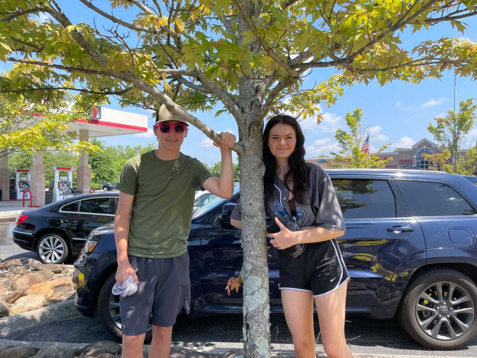 Isaac Parnell, 16, and Catelyn Pehrson, 16, take a brief break under a tree at the Hardin Valley Academy Band car wash at Food City on Middlebrook Pike Saturday, July 23, 2022.