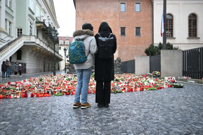 People light candles and place flowers at a makeshift memorial in front of the building of the Faculty of Philosophy of Charles University for the victims of the deadly shooting. On Thursday afternoon, a shooter opened fire at a university in central Prague, killing at least 14 people and injuring 25, 10 of whom were critically. Kamaryt Michal/CTK/dpa