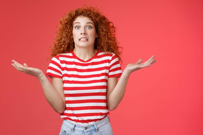 Redhead girl shrugs with her hands up