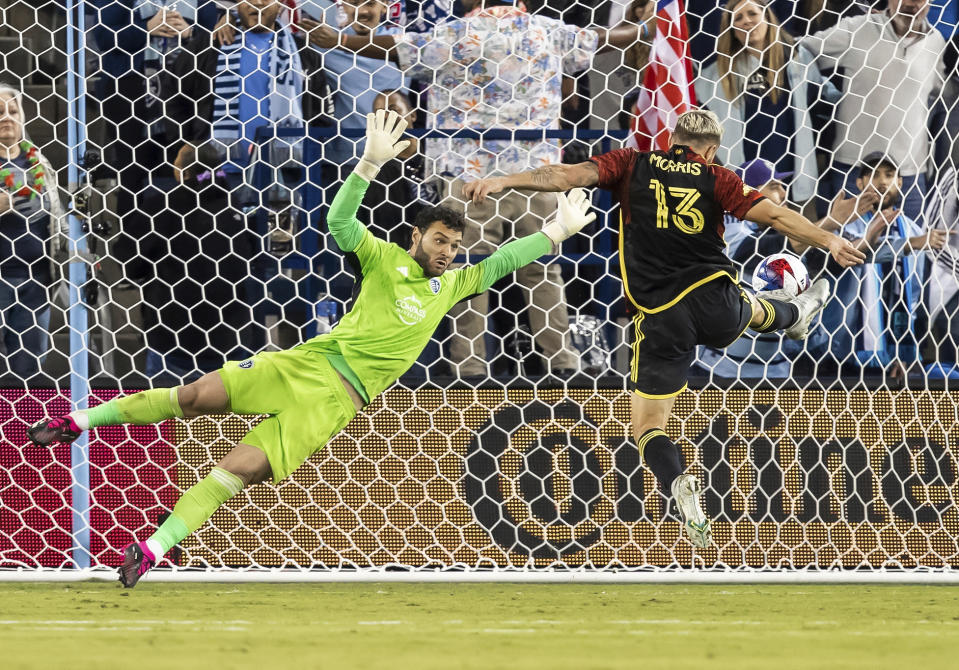 Seattle Sounders forward Jordan Morris (13) scores his third goal of an MLS soccer match against Sporting Kansas City goalkeeper John Pulskamp, left, during the second half Saturday, March 25, 2023, in Kansas City, Kan. (AP Photo/Nick Tre. Smith)