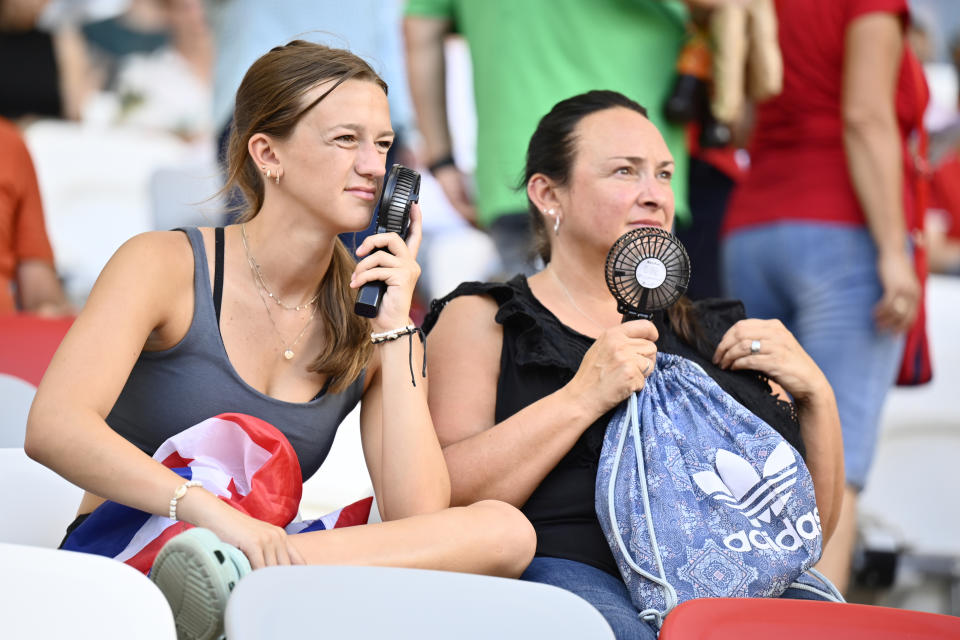 FILE - Spectators keep themselves cool by using small portable fans as they watch the World Athletics Championships in Budapest, Hungary, Monday, Aug. 21, 2023. (AP Photo/Denes Erdos, File)