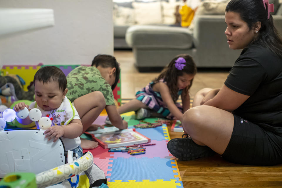 Venezuelan asylum-seeker Oriana Marcano plays with her children, from left, Adonai, 8-months; Stefano, 5, and Amaloha, 3, in El Paso, Texas, Friday, May 12, 2023. When her family was lost in Panama's Darien Gap last year, her husband, Luis Lopez, often knelt in the mud to beg God not to abandon them. Now safe in El Paso after fleeing Venezuela and hosted by a Catholic bishop, the family awaits Lopez's sister and mother who also fled the country and crossed through the jungle, but with the end of U.S. pandemic-era asylum regulations and new migration rules looming over them. (AP Photo/Andres Leighton)