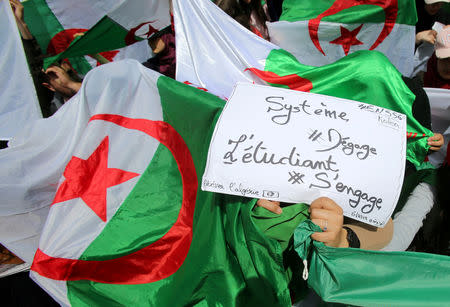 FILE PHOTO: Demonstrators hold flags and banners during anti government protests in Algiers, Algeria April 23, 2019. The banner reads "Government go away - students take over". REUTERS/Ramzi Boudina/File photo