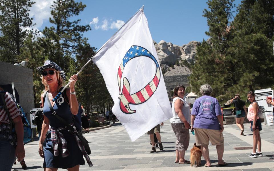 A Donald Trump supporter holding a QAnon flag visits Mount Rushmore National Monument on July 1 - Scott Olson /Getty Images North America 