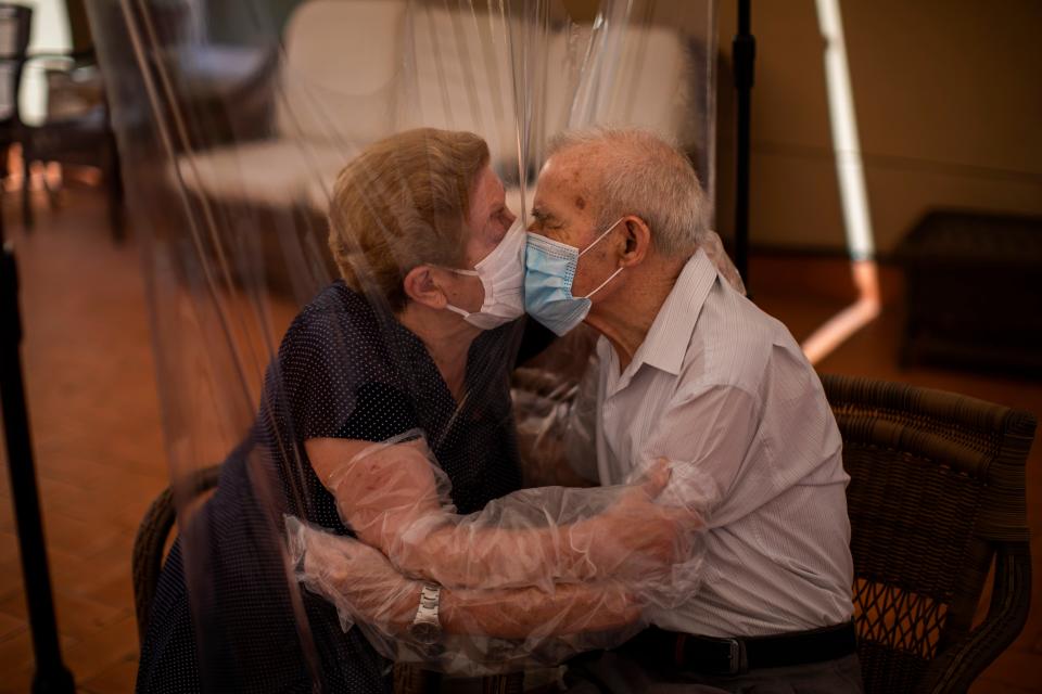 Agustina Cañamero, 81, and Pascual Pérez, 84, hug and kiss through a plastic film screen to avoid contracting the new coronavirus at a nursing home in Barcelona, Spain, Monday, June 22, 2020. The Ballesol Fabra i Puig elderly care center installed the screens to resume relatives' visits to residents 102 days after a strict, nationwide lockdown separated them. As she and her husband broke out into tears while kissing through layers of protective masks and the transparent plastic film, Cañamero said that the couple had never spent such long time with no physical contact in 59 years of marriage.