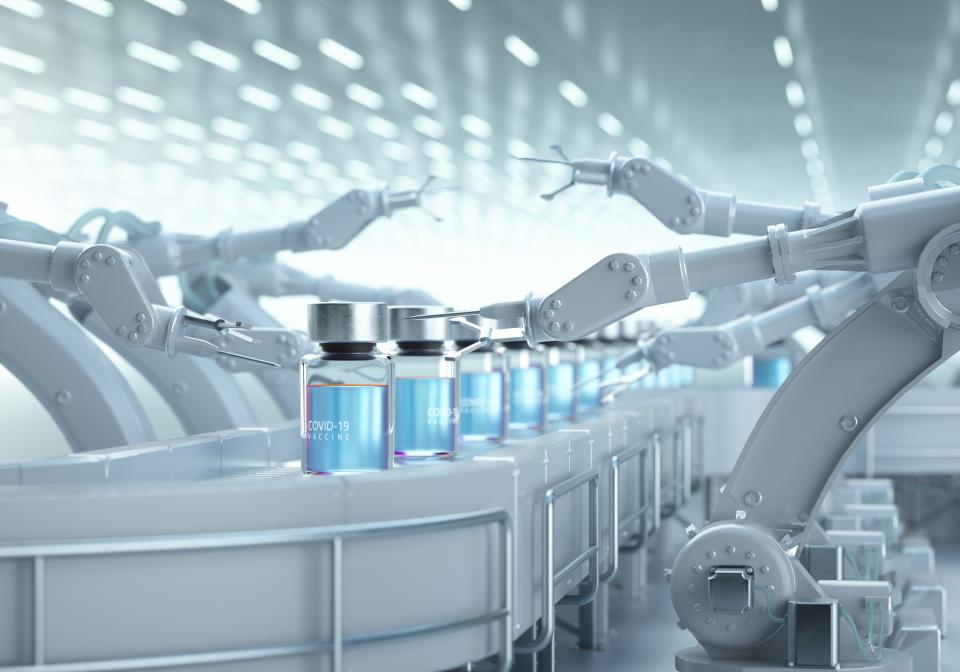 Digital generated image of COVID-19 vaccine bottles standing on robotic production line.