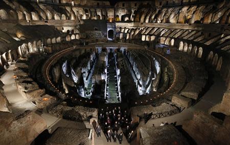 A faithful carries a cross as Pope Francis leads the Via Crucis (Way of the Cross) procession during Good Friday celebrations in front of the Colosseum in Rome April 18, 2014. REUTERS/Tony Gentile