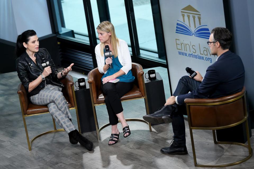 Three people on a stage with microphones, in front of a sign that says 'Erin's Law.'