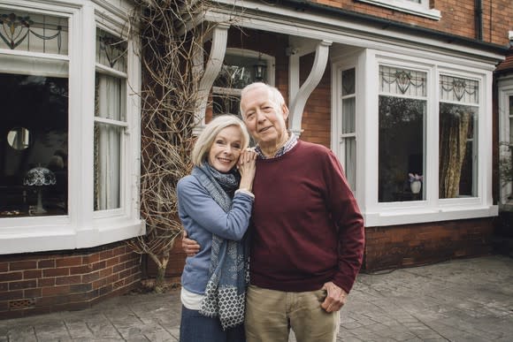 Senior couple standing outside of home