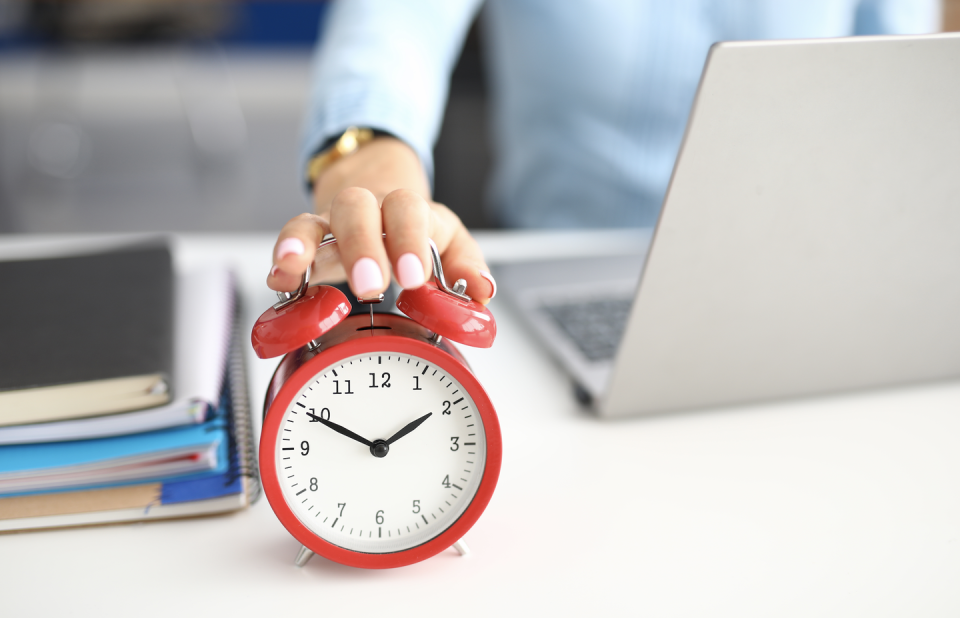 a person holding a red alarm clock