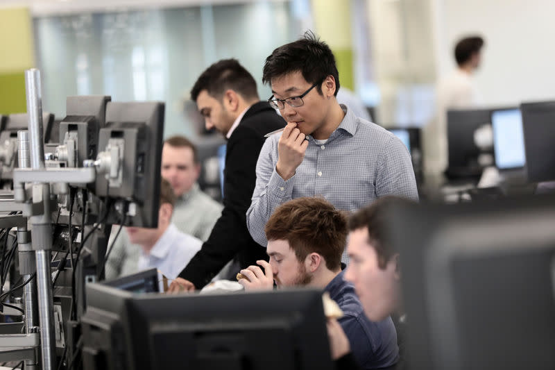 FILE PHOTO: Traders looks at financial information on computer screens on the IG Index trading floor in London, Britain February 6, 2018. REUTERS/Simon Dawson
