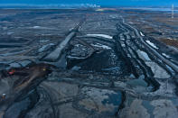 As twilight falls on the Alberta tar sands, the stripped landscape takes on an oily blue tint.