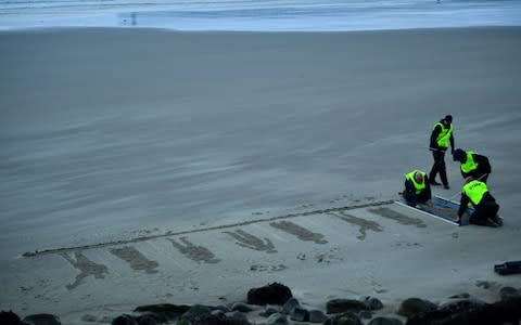 Volunteers rake the sand as they draw depictions of those killed in WW1, part of Danny Boyle's Pages of The Sea celebrations, on Sunny Sands Beach in Folkestone - Credit: Reuters