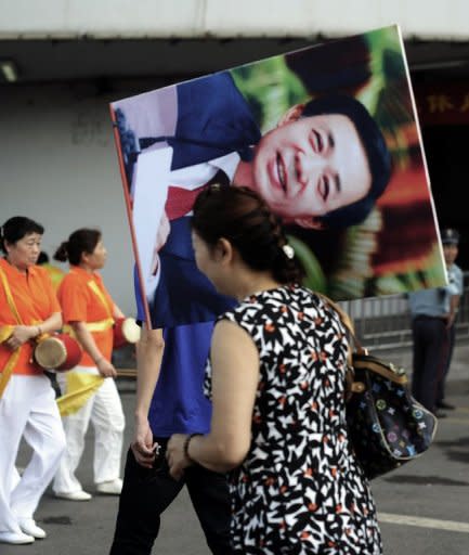 File photo shows a Chinese woman in Chongqing carrying a protrait of Bo Xilai after a "red" culture session, where workers gather to sing revolutionary songs. Bo, until recently a rising political star, was known in for busting gangs and reviving Maoist ideals in Chongqing