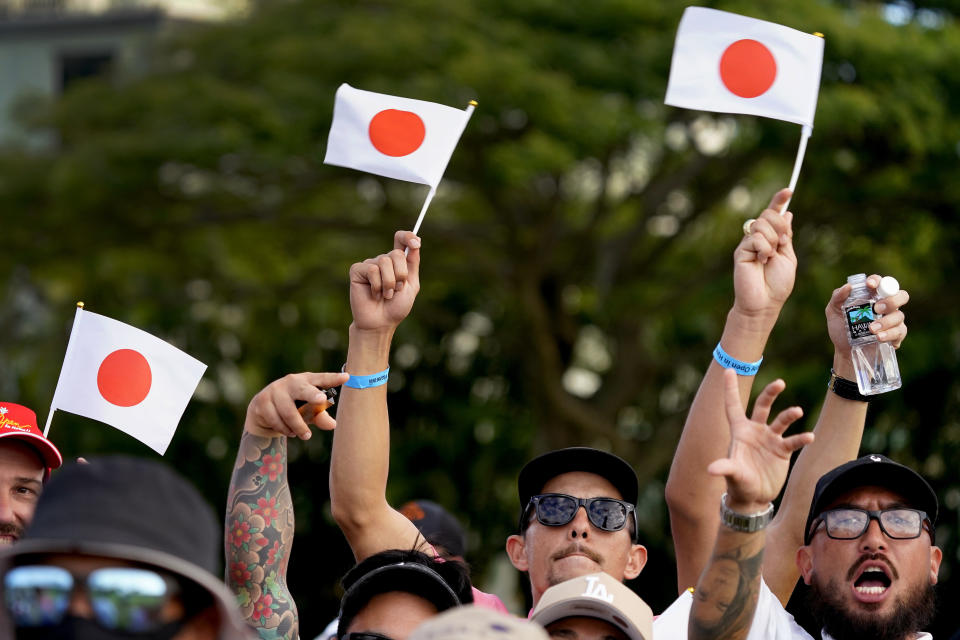 Fans wave Japanese flags as they cheer for Hideki Matsuyama on the 18th green during the final round of the Sony Open golf tournament, Sunday, Jan. 16, 2022, at Waialae Country Club in Honolulu. (AP Photo/Matt York)