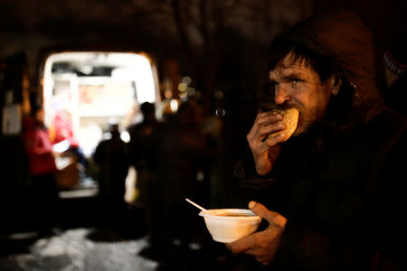 A man eats soup and bread near a van of 'Nochlezhka' charity organization as volunteers distribute meals for homeless people in St. Petersburg, Russia December 5, 2018. REUTERS/Anton Vaganov