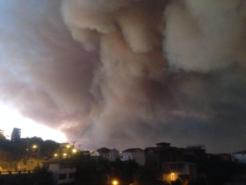 Eine riesige Rauchwolke steht über den vom Feuer bedrohten Häusern der Stadt. Foto: EPA