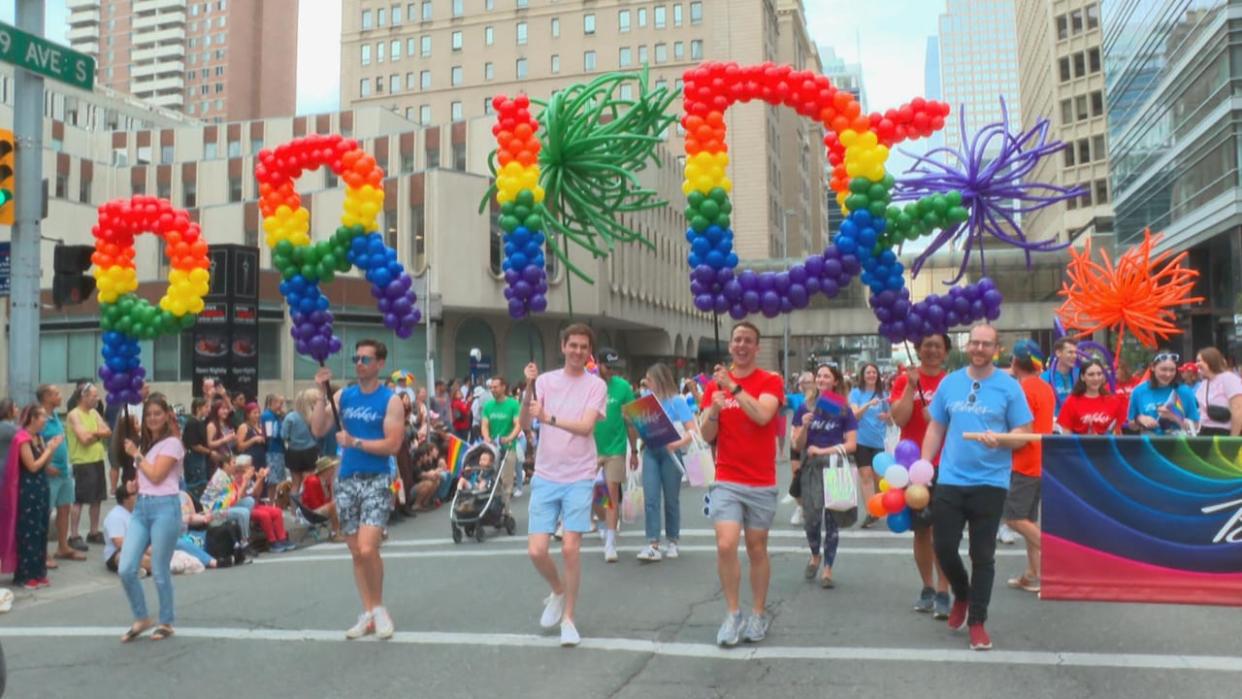 A photo of Calgary's 2023 Pride parade shows people marching downtown. Calgary Pride, along with 13 other Pride organizations, have banned the UCP and Premier Danielle Smith from all 2024 Pride events. (Helen Pike/CBC - image credit)