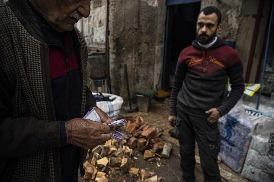 A man buys firewood in Aleppo, Syria, Sunday, Dec. 15, 2022. Syria's economy has hit its lowest point since the country's civil war began nearly 12 years ago, with severe fuel shortages in both government and rebel-held areas, spiraling inflation and the Syrian currency hitting an all-time low on the black market. (AP Photo/Baderkhan Ahmad)