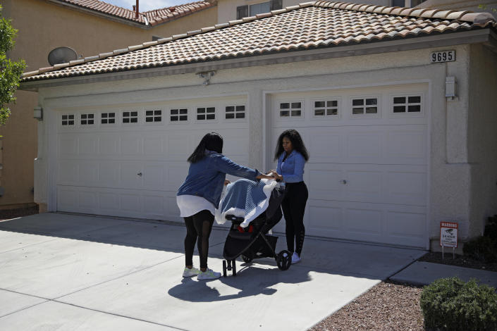 In this April 17, 2020, photo, Kimberly Ireland, left, helps her daughter Kyla Ireland, right, cover Kyla's three-week-old baby before going on a walk in Las Vegas. A walk around the neighborhood is one of the rare times they leave the house during the coronavirus outbreak. Kimberly Ireland was laid off from her job as a bell desk dispatcher at the Mirage casino-resort, where she worked for a decade. (AP Photo/John Locher)
