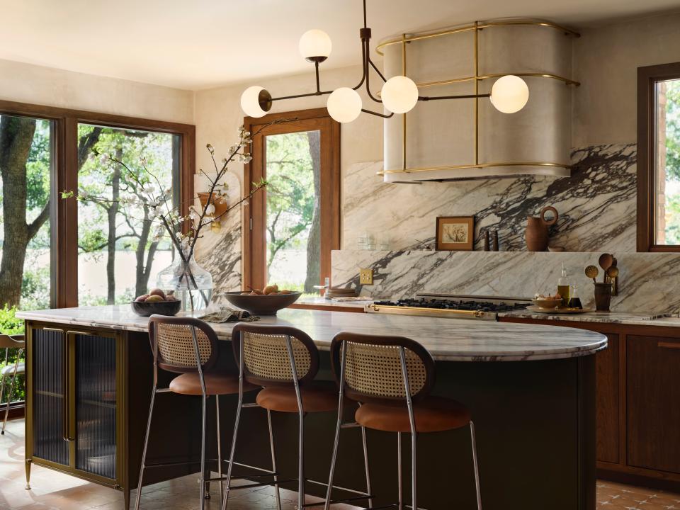 A custom-built powder-coated green island centers the kitchen, which also features plastered walls and a brass vent hood cage.