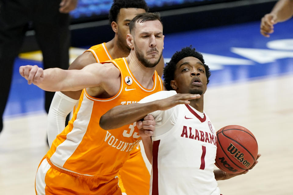 Alabama's Herbert Jones (1) drives against Tennessee's Uros Plavsic (33) in the first half of an NCAA college basketball game in the Southeastern Conference Tournament Saturday, March 13, 2021, in Nashville, Tenn. (AP Photo/Mark Humphrey)