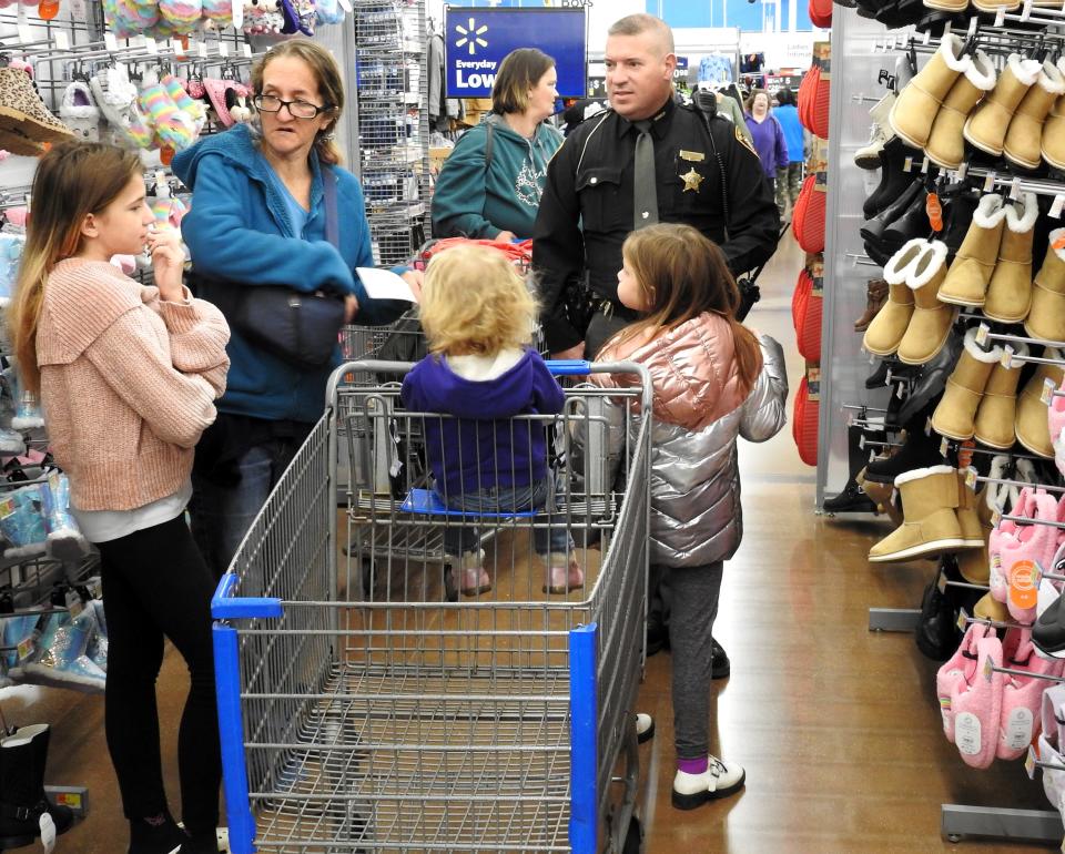 Virginia Almack and her children Kari, 11, Annaliese 18 months and Becky, 9, shop with Lt. J.D. Hardway for the Coshocton Salvation Army's annual Christmas Castle program at the Coshocton Walmart.