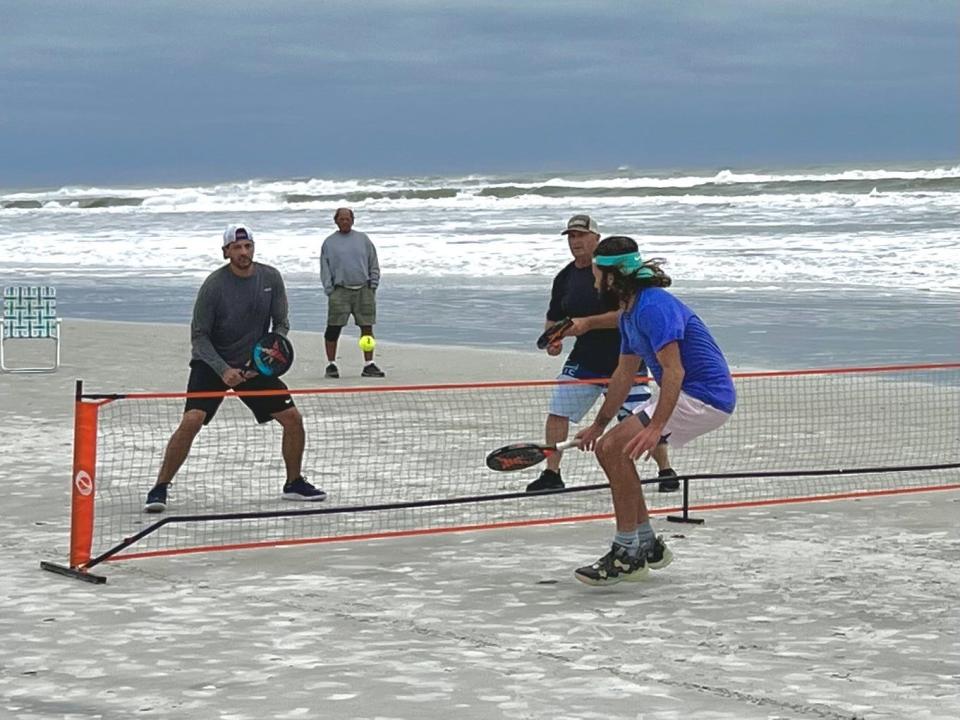 Clay Schwartz of Los Angeles (blue shirt) returns a shot at the net to Avery Merulla and Tony Gaines during 50th anniversary of the National Beach Pop Tennis tournament in St. Augustine.