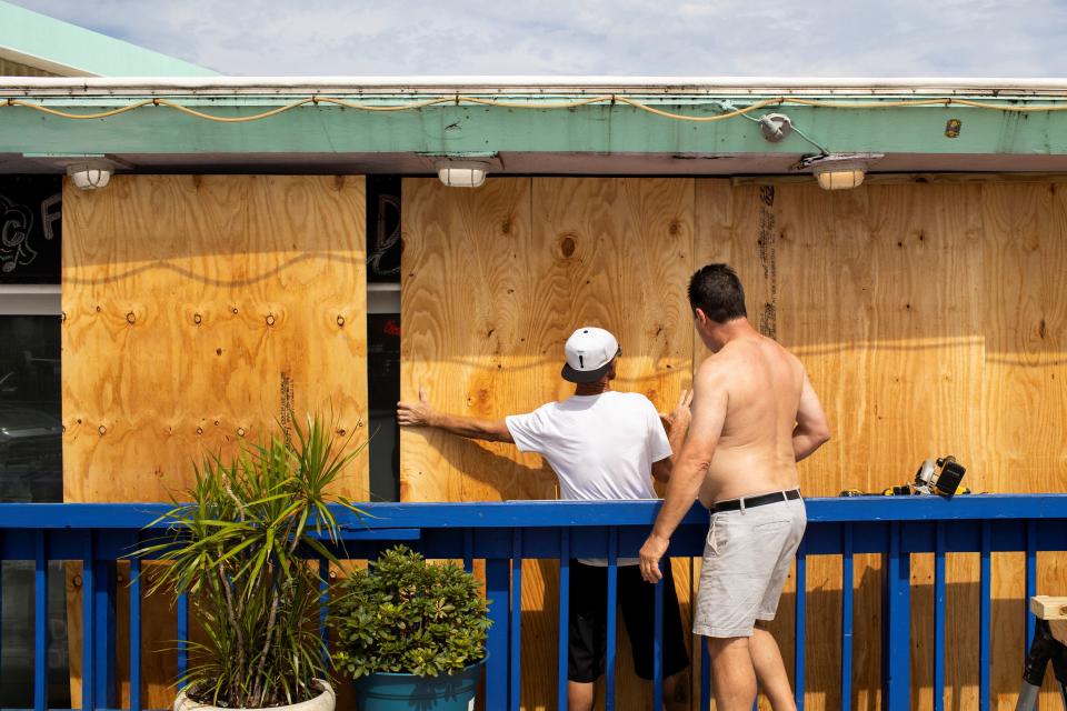 Men board up the windows of a bar ahead of the arrival of Hurricane Idalia, in Cedar Key, Florida, on Tuesday (REUTERS)