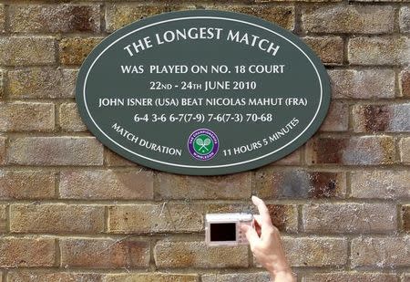 A spectator photographs a plaque attached to the wall of number 18 court after the match in 2010 that lasted more than 11 hours, between John Isner of the U.S. and Nicolas Mahut of France, at the Wimbledon tennis championships in London June 21, 2011. REUTERS/Suzanne Plunkett Files