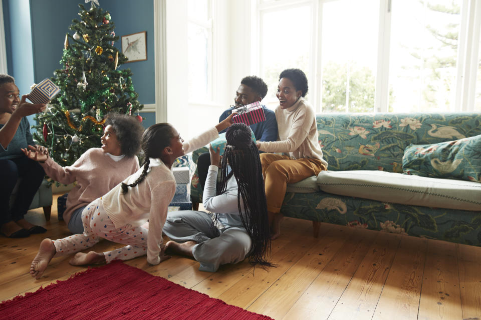 Happy family and friends giving Christmas presents to each other while sitting at home