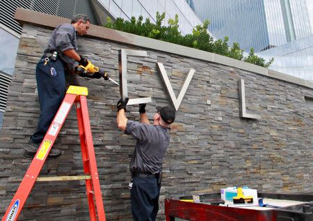 Joe Luccathetti (L) and Robert Fitting, employees of the Revel Casino Hotel remove signage from its wall along the boardwalk in Atlantic City, New Jersey September 1, 2014. REUTERS/Tom Mihalek