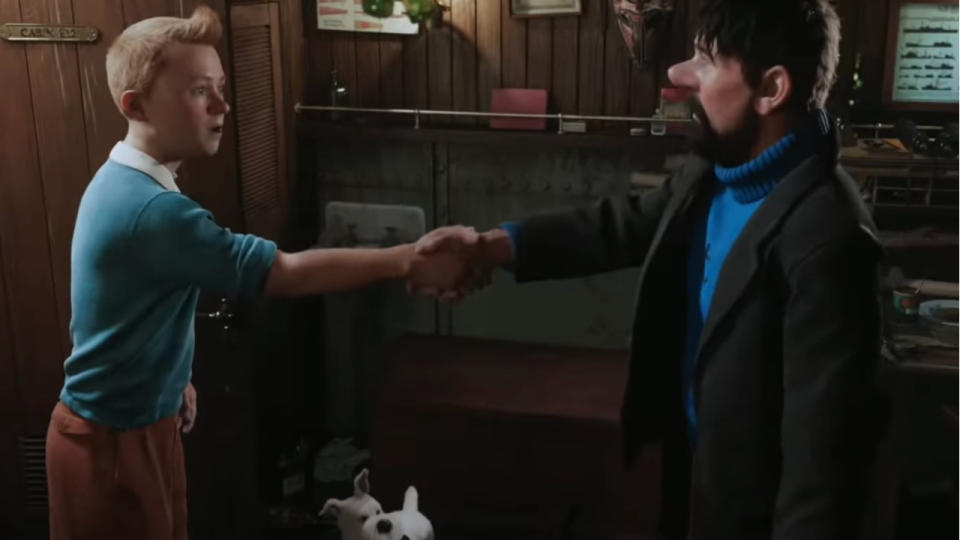 Tintin and Captain Haddock shake hands while Snowy looks on in The Adventures of Tintin.