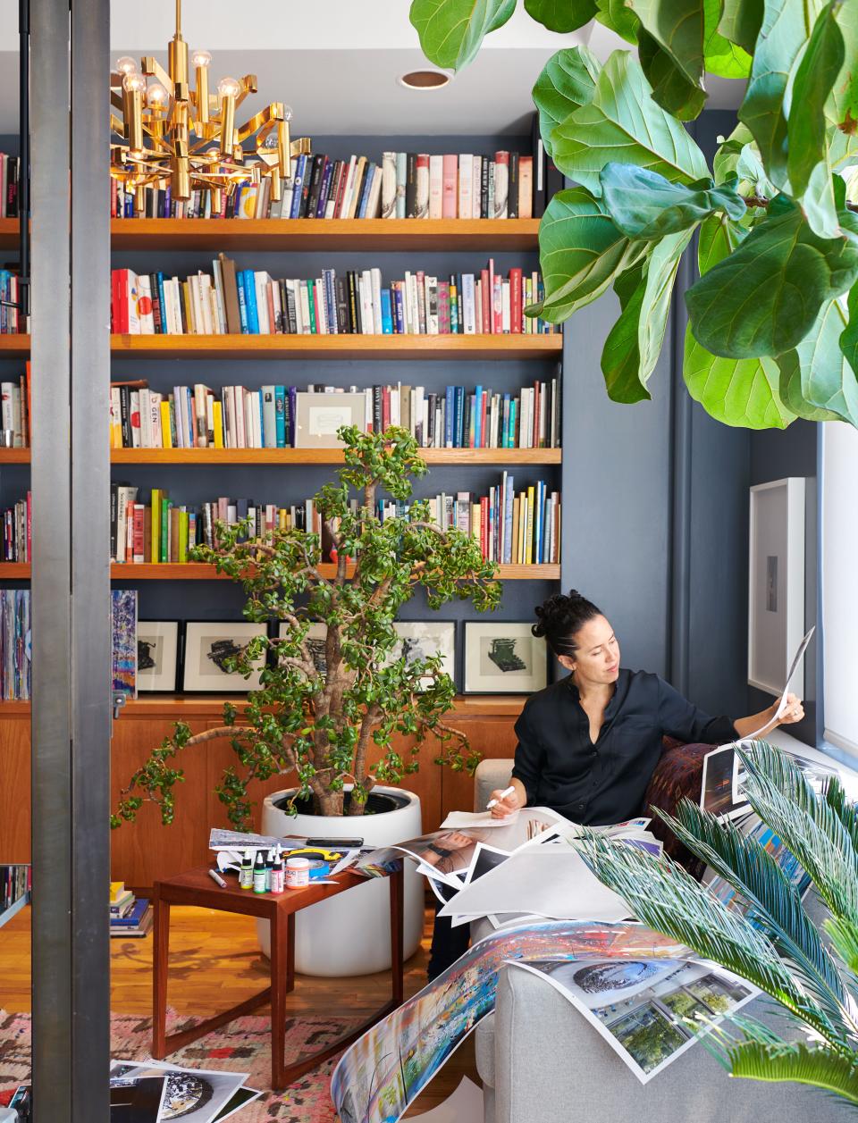 Sarah Sze, working in the library turned Studio under a Robert Sonneman chandelier. on lower shelf, prints by William Kentridge.