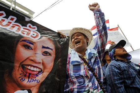 Farmers hold a defaced poster of Thai Prime Minister Yingluck Shinawatra as they protest outside her temporary office in Bangkok February 17, 2014. REUTERS/Chaiwat Subprasom