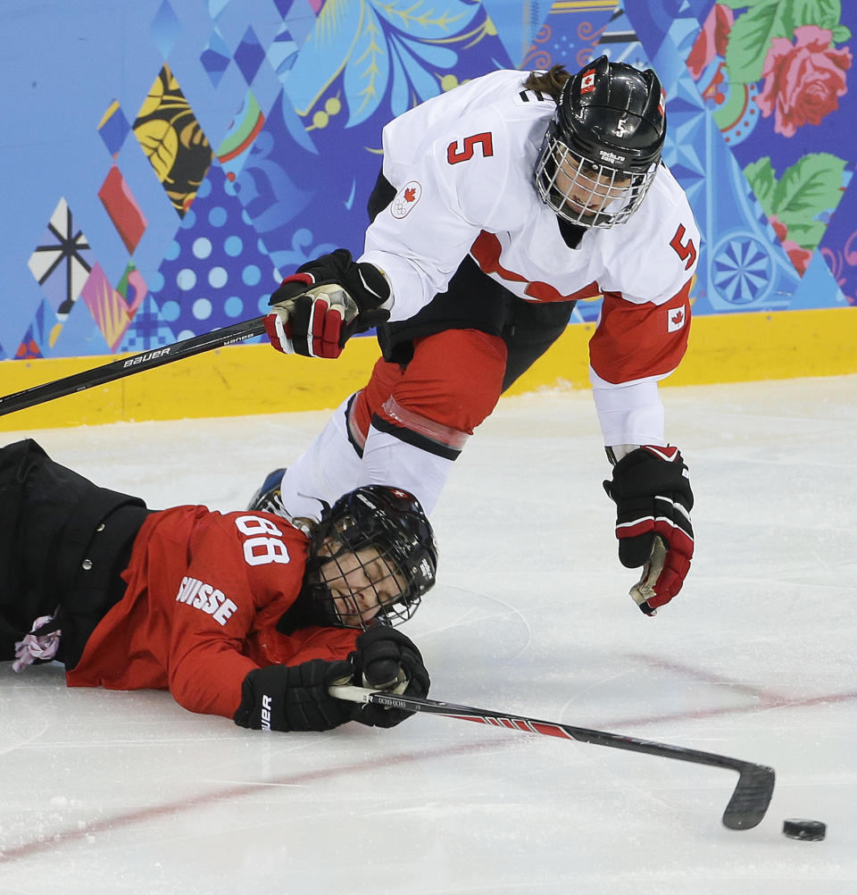 Phoebe Stanz of Switzerland (88) dives for the puck against Lauriane Rougeau of Canada during the second period of the 2014 Winter Olympics women's semifinal ice hockey game at Shayba Arena, Monday, Feb. 17, 2014, in Sochi, Russia. (AP Photo/Matt Slocum)