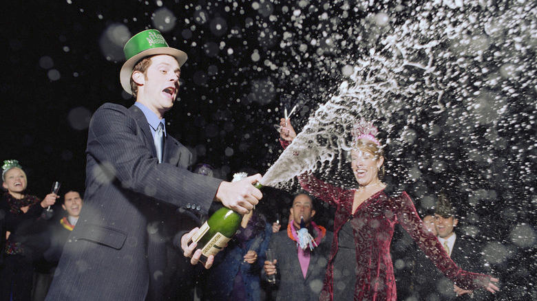 Man spraying a bottle of champagne at a party