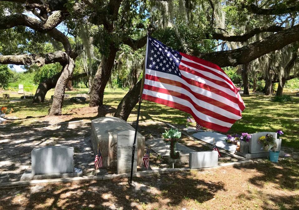 In a photo from 2019, a U.S. flag flies alongside gravesites beneath an oak canopy at J.N. Tucker Memorial Cemetery in Melbourne.