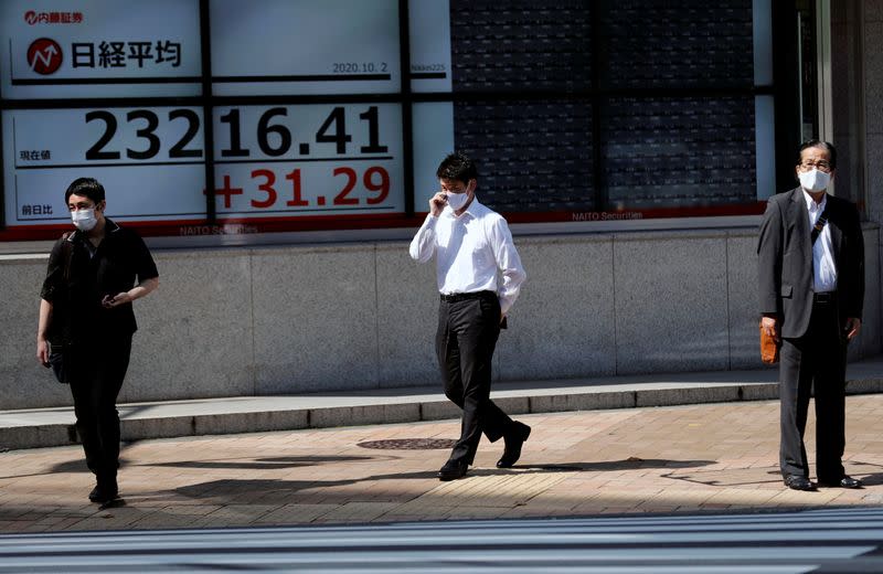 FILE PHOTO: People stand in front of a screen showing Nikkei index outside a brokerage in Tokyo