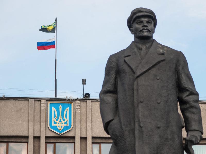 Hinter einer Lenin-Statue weht die russische Fahne über einem besetzten Verwaltungsgebäude. Foto: Roman Pilipey